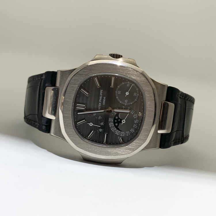 PATEK PHILIPPE 百达翡丽 NAUTILUS 运动系列，5712G-001。40毫米表径，18K白金表壳，深灰色面盘，覆荧光涂层金质立体时标，指针式日期显示、月相显示、动力储备显示功能，Cal.240 PS IRM C LU自动上弦机械机芯，动力储备48小时。专柜定价：318800元。 全套附件齐全。